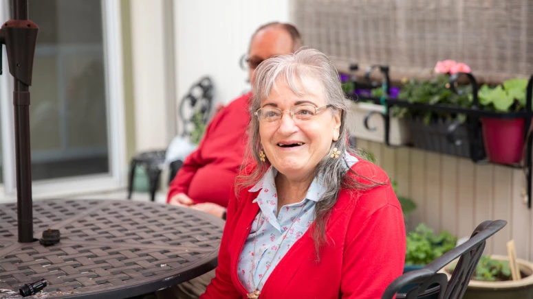 Senior woman smiling while seated at a patio.