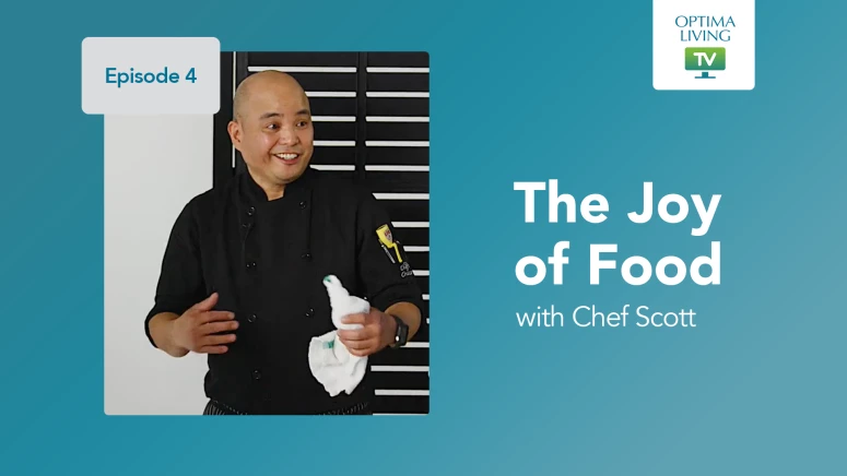 An asian chef wearing a black chef jacket and talking